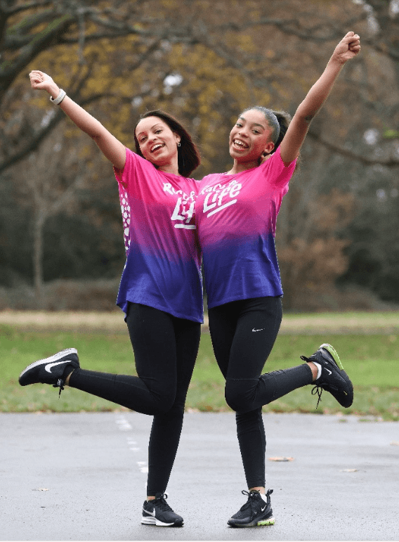 Crystal is hugging a friend. They are both wearing pink and purple Race for Life T-shirts, smiling and posing for the camera.