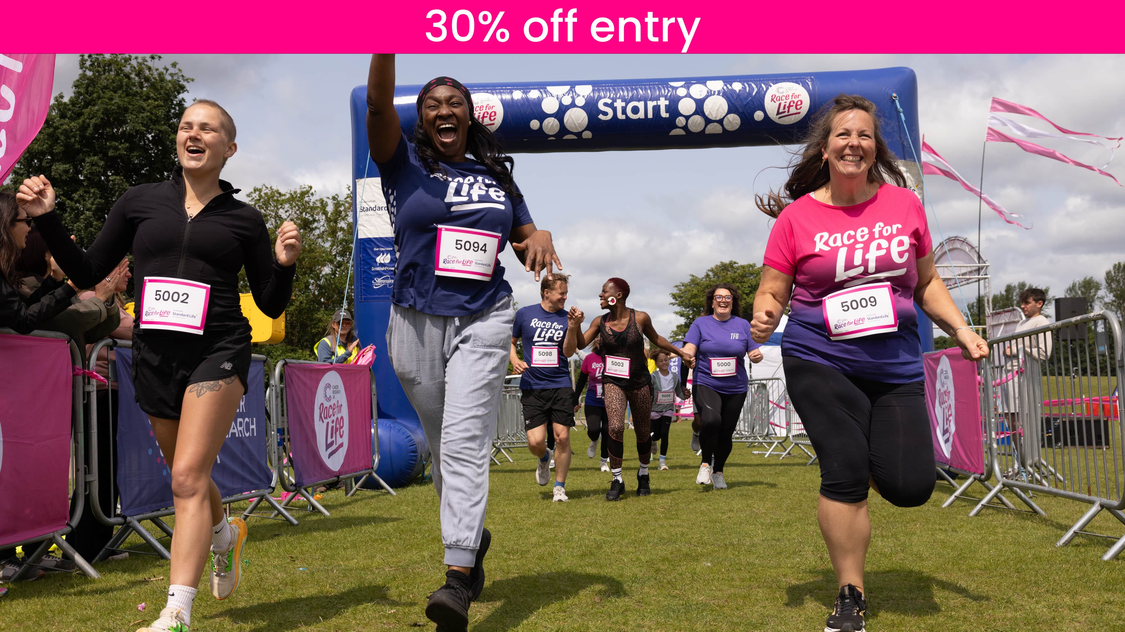 a group wearing Race for Life T-shirts beginning their race at the start line with smiles on their faces.