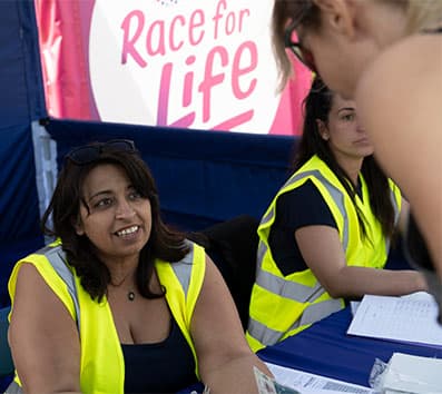Volunteers sitting at a table in the enquiries tent, answering participants' questions.