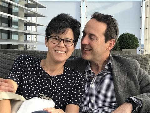 Lin, a Race for Life participant and adrenal gland cancer survivor, is sat with another person. They're both smiling.