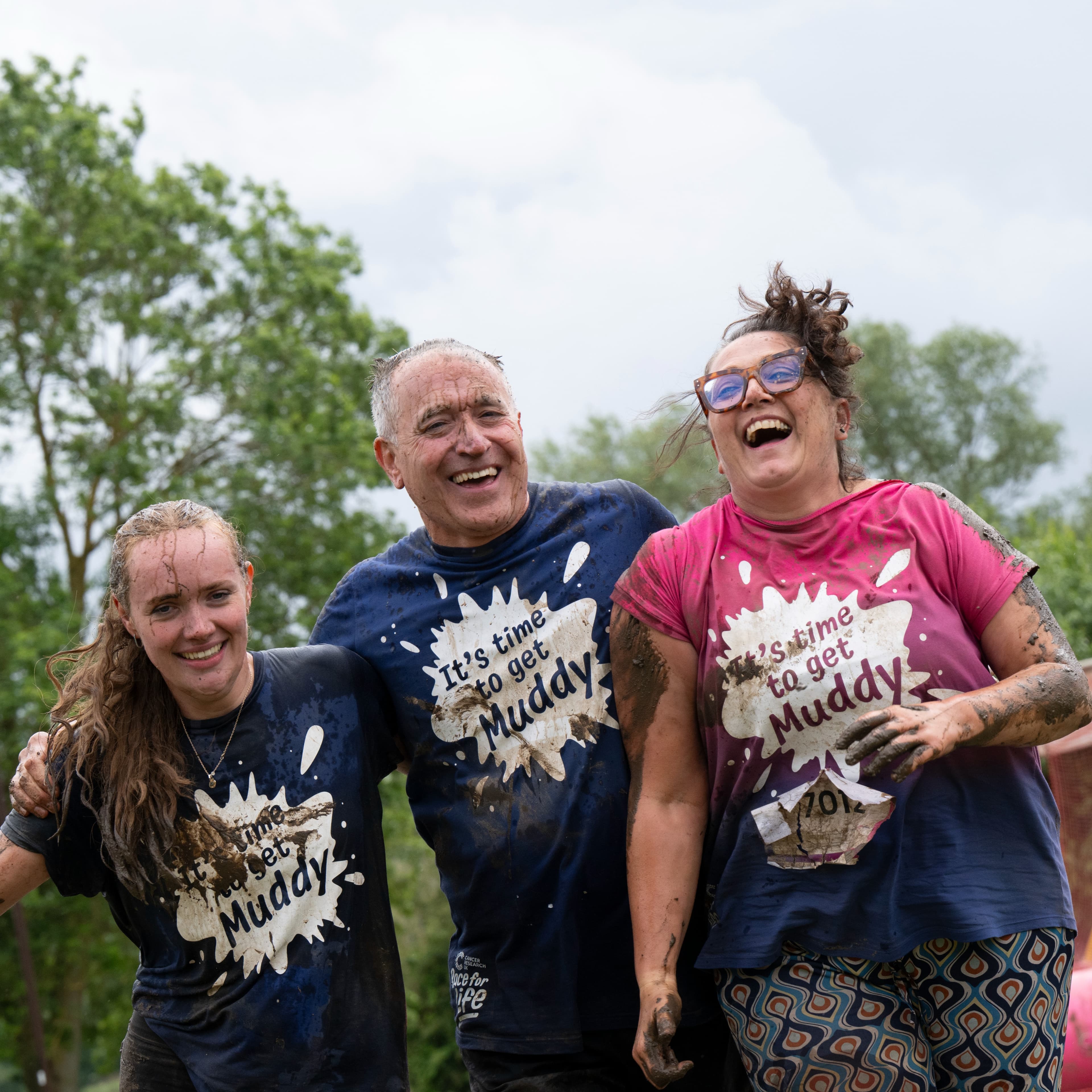 Group of people covered in mud, smiling.