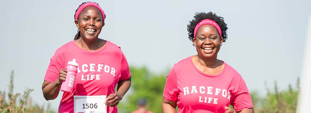 A photo of two women wearing Race for Life t-shirts, running, and looking happy.