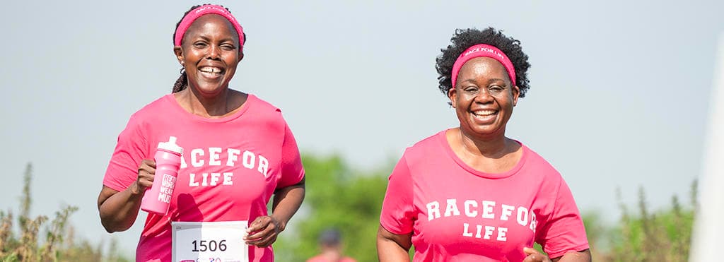 A photo of two women wearing Race for Life t-shirts, running, and looking happy.