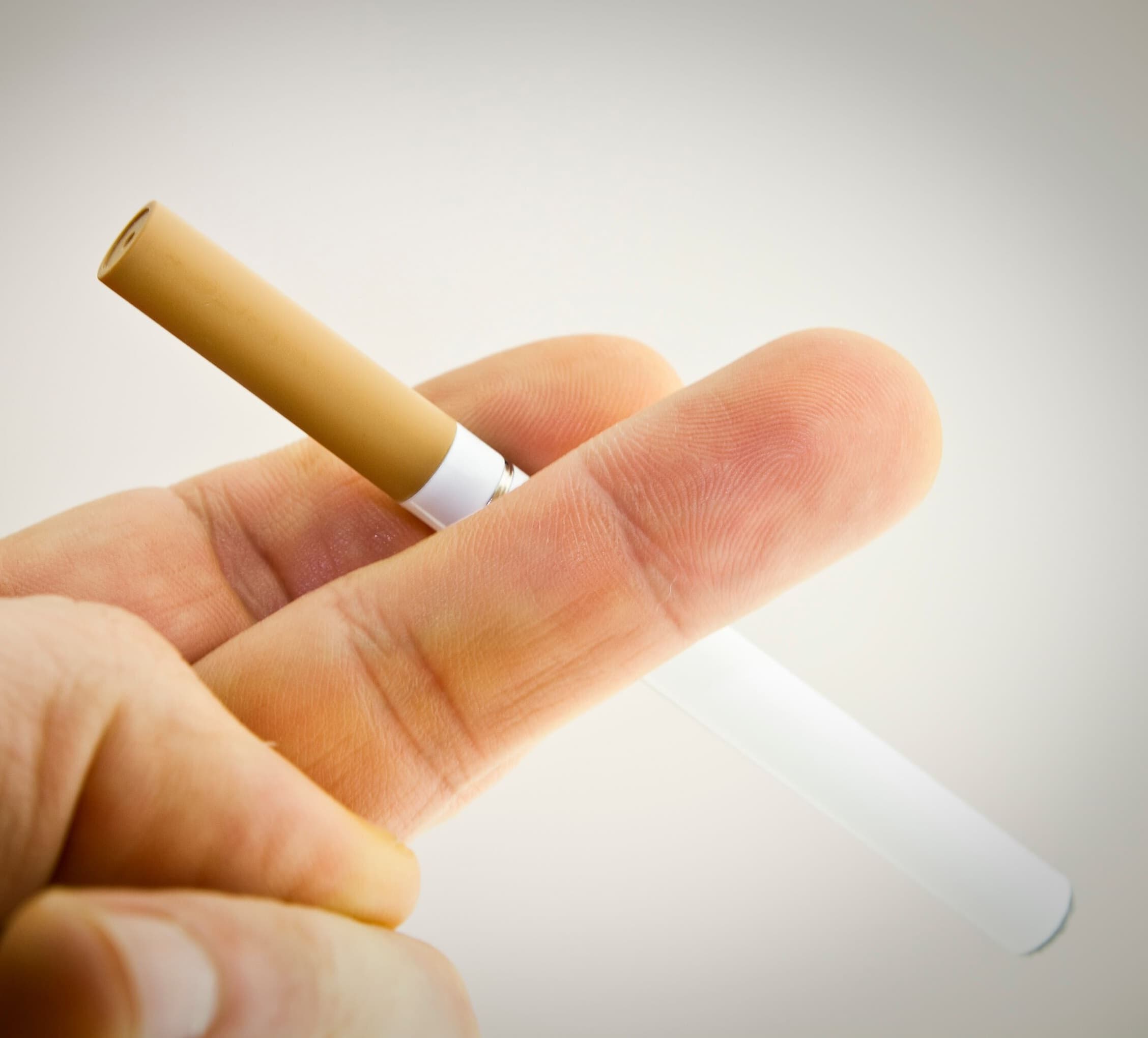 A man smoking an orange E-cigarette.