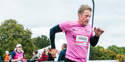 A man in a pink t-shirt running a 10k event