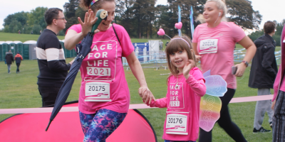 A woman and her daughter waving taking part in a 3k event