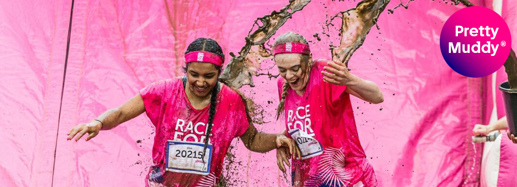 Women covered in mud after going down an obstacle
