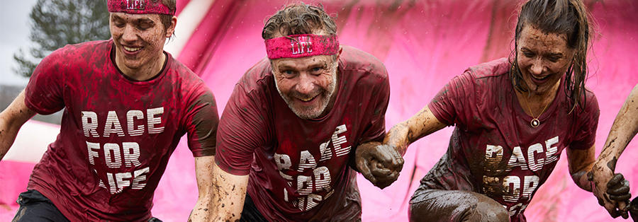 Photo of three people at the bottom of a slide as they take part in Pretty Muddy