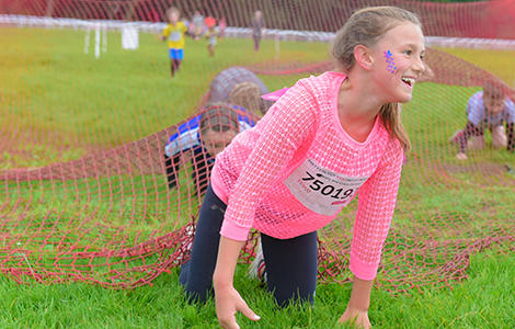 Girls crawling under netting in Pretty Muddy Kids obstacle course