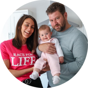 Carly wearing a pink Race for Life t-shirt with her husband and daughter